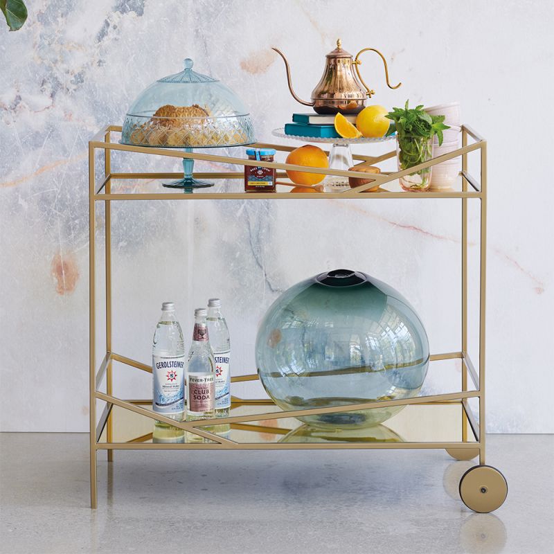 A luxury bar cart by Caracole with a glamorous gold finish