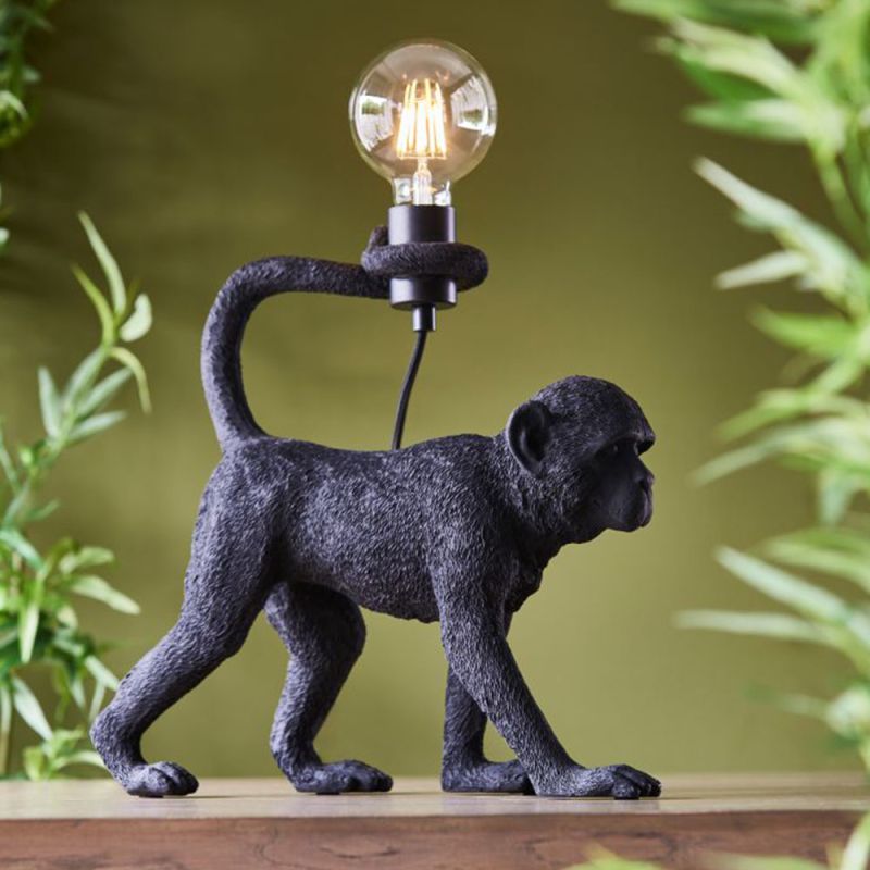 Monkey-shaped lamp with a bulb held in the tail