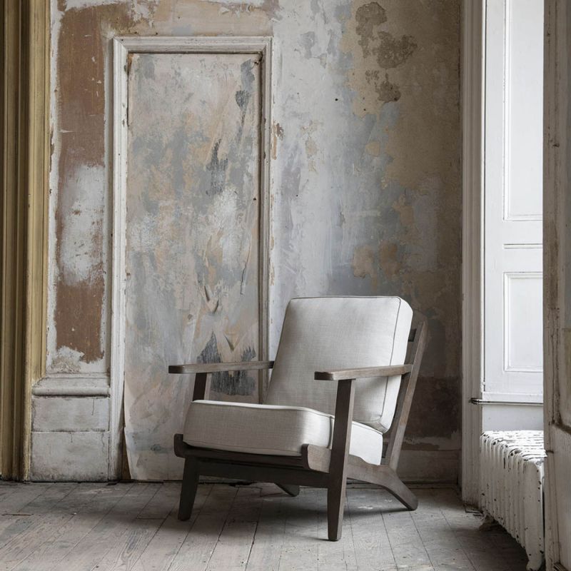 A stylish armchair with an ash wood frame and soft cream upholstery 