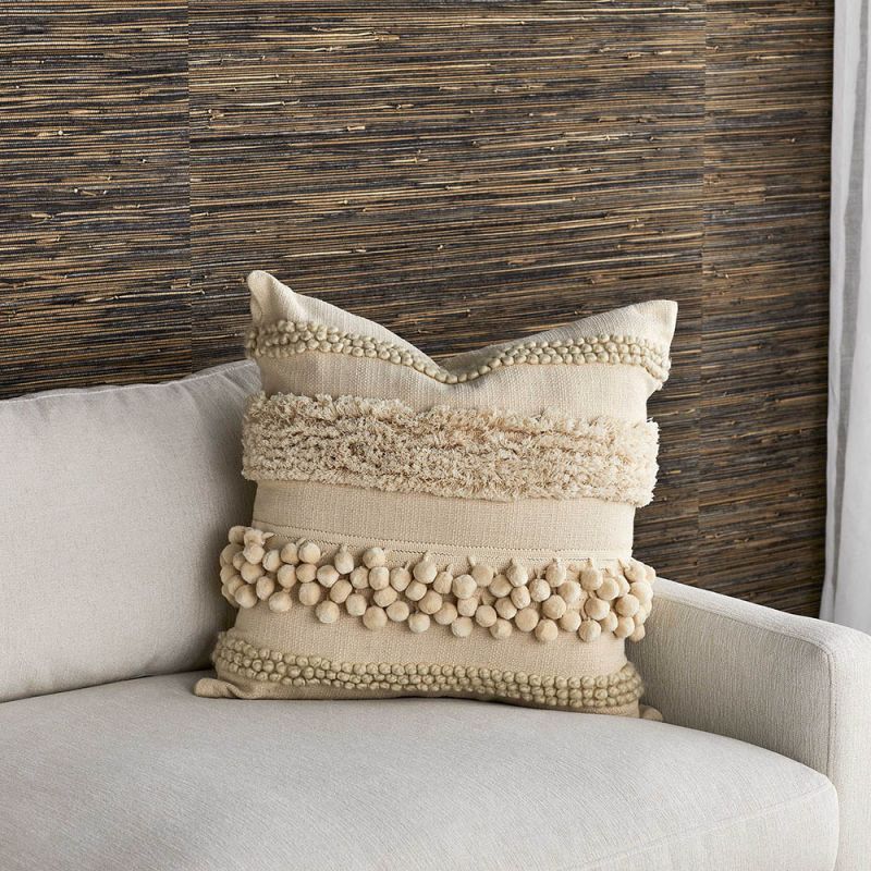 Cream coloured cushion with rows of various tufted textures and bobbles