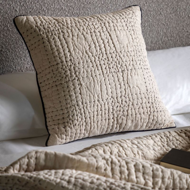 Beige quilted cushion with black stitching
