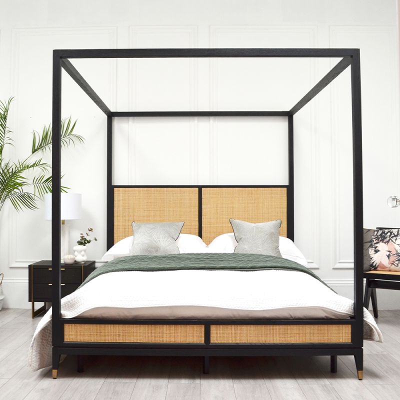 A colonial, tropics-inspired bed with four posters, rattan detailing and an ebony finish