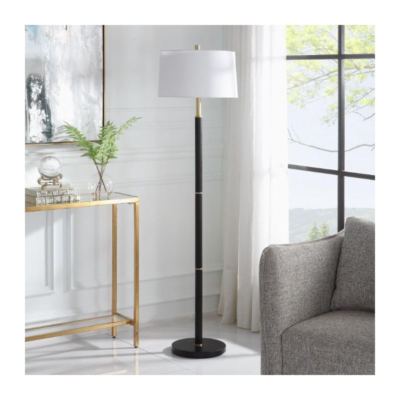 The Troy Floor Lamp, featuring a minimalist design with gold rings along its slender body, is finished with a subtly tapered hardback shade in soft white linen with delicate slubbing, exuding refined elegance.