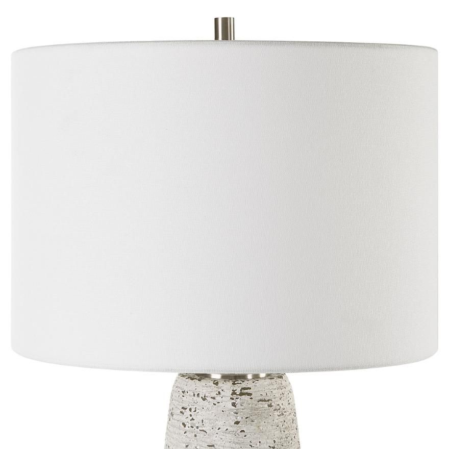 This tapered ceramic lamp has a distressed off-white finish, brushed nickel accents, and a white linen shade, adding timeless elegance to any space.
