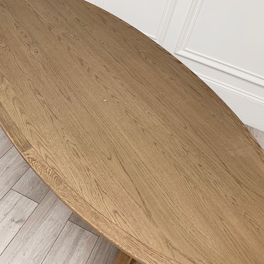 Oval shape wooden dining table with some marks on surface