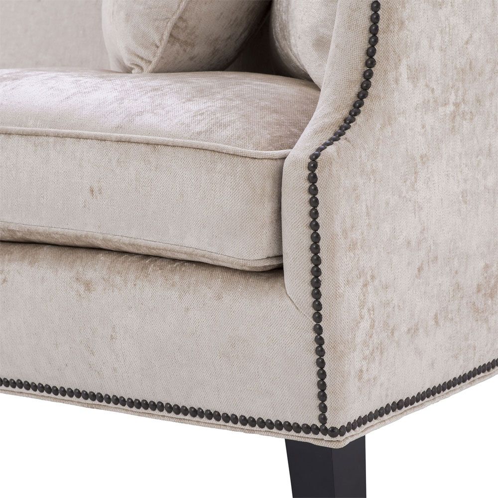 velvety off-white 3 seater sofa with bronze accents and black tapered legs 