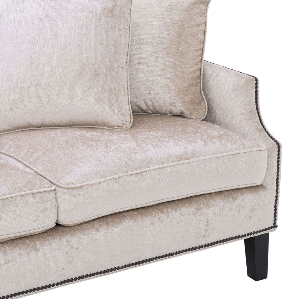 velvety off-white 3 seater sofa with bronze accents and black tapered legs 