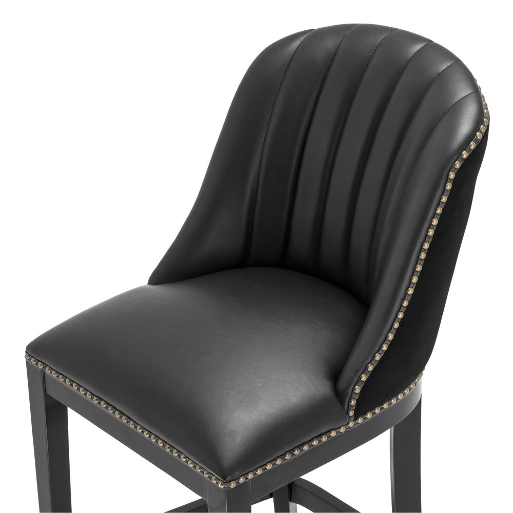 A chic black leather and velvet bar stool with antique brass studding