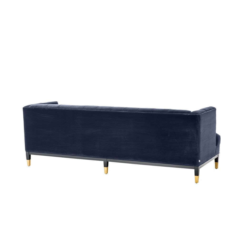 dark blue deep-buttoned sofa with velvet upholstery and black legs with gold accents