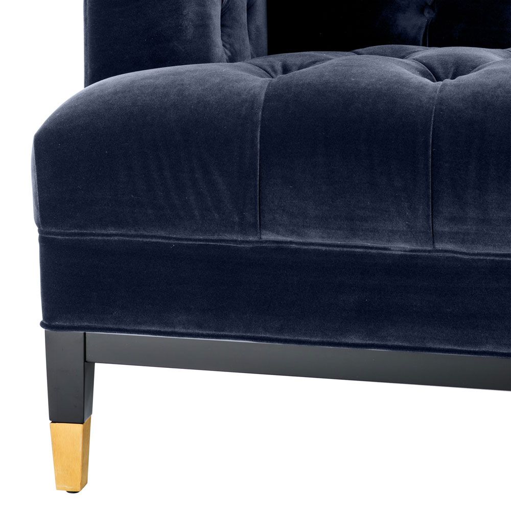 dark blue deep-buttoned sofa with velvet upholstery and black legs with gold accents