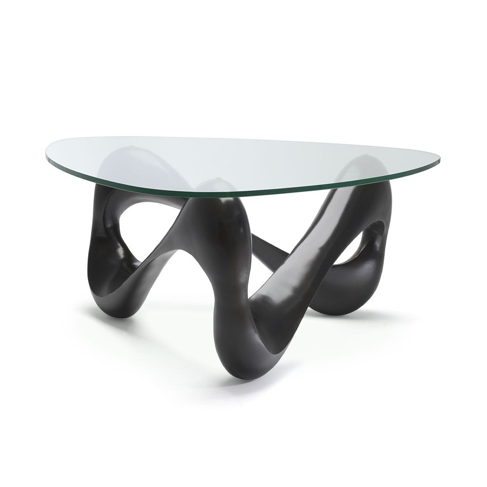 A statement coffee table by Eichholtz with a bold vintage brass base and clear glass top