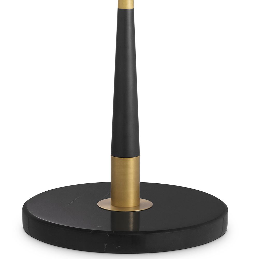 A contemporary table lamp by Eichholtz with a stylish design featuring an antique brass finish, an open free shape and a black cylindrical shade