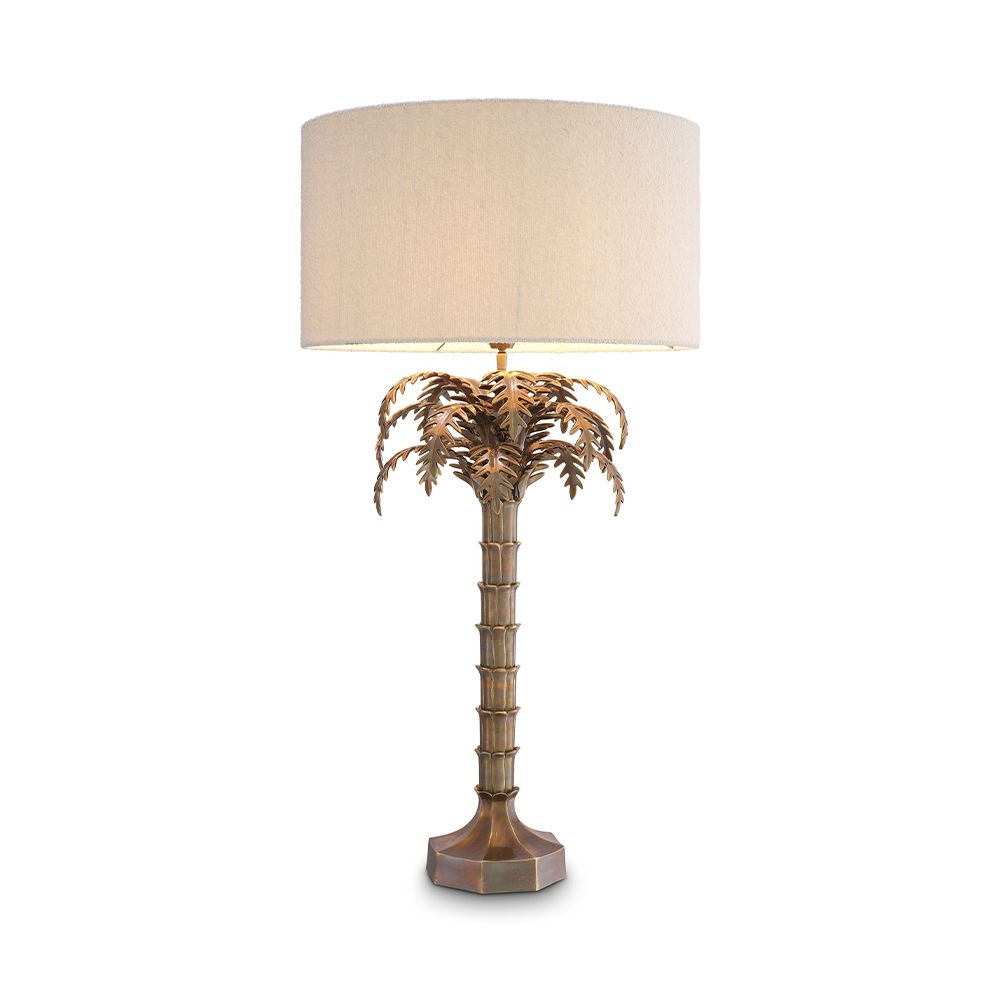 A decorative side lamp by Eichholtz with a boucle cream shade and an Art-Deco tropical tree base with a vintage brass finish