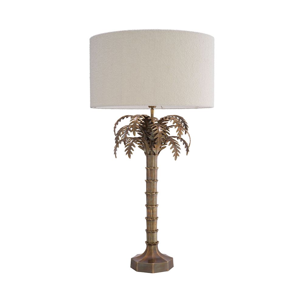 A decorative side lamp by Eichholtz with a boucle cream shade and an Art-Deco tropical tree base with a vintage brass finish