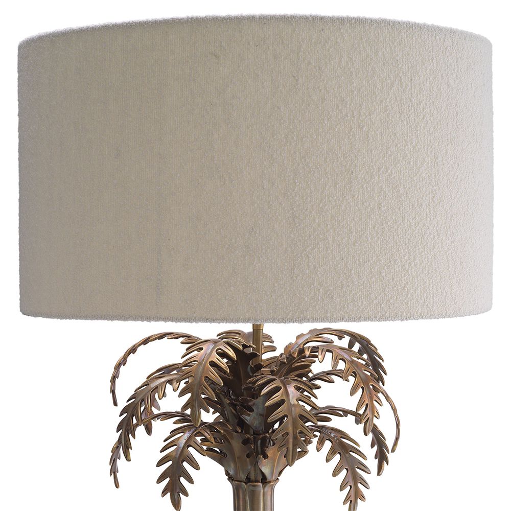 A decorative side lamp by Eichholtz with a boucle cream shade and an Art-Deco tropical tree base with a vintage brass finish