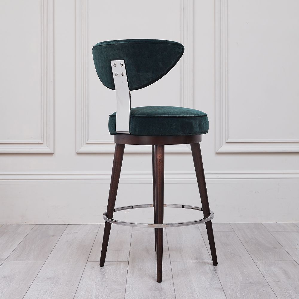 A luxurious, upholstered bar stool with tapered legs and silver accents