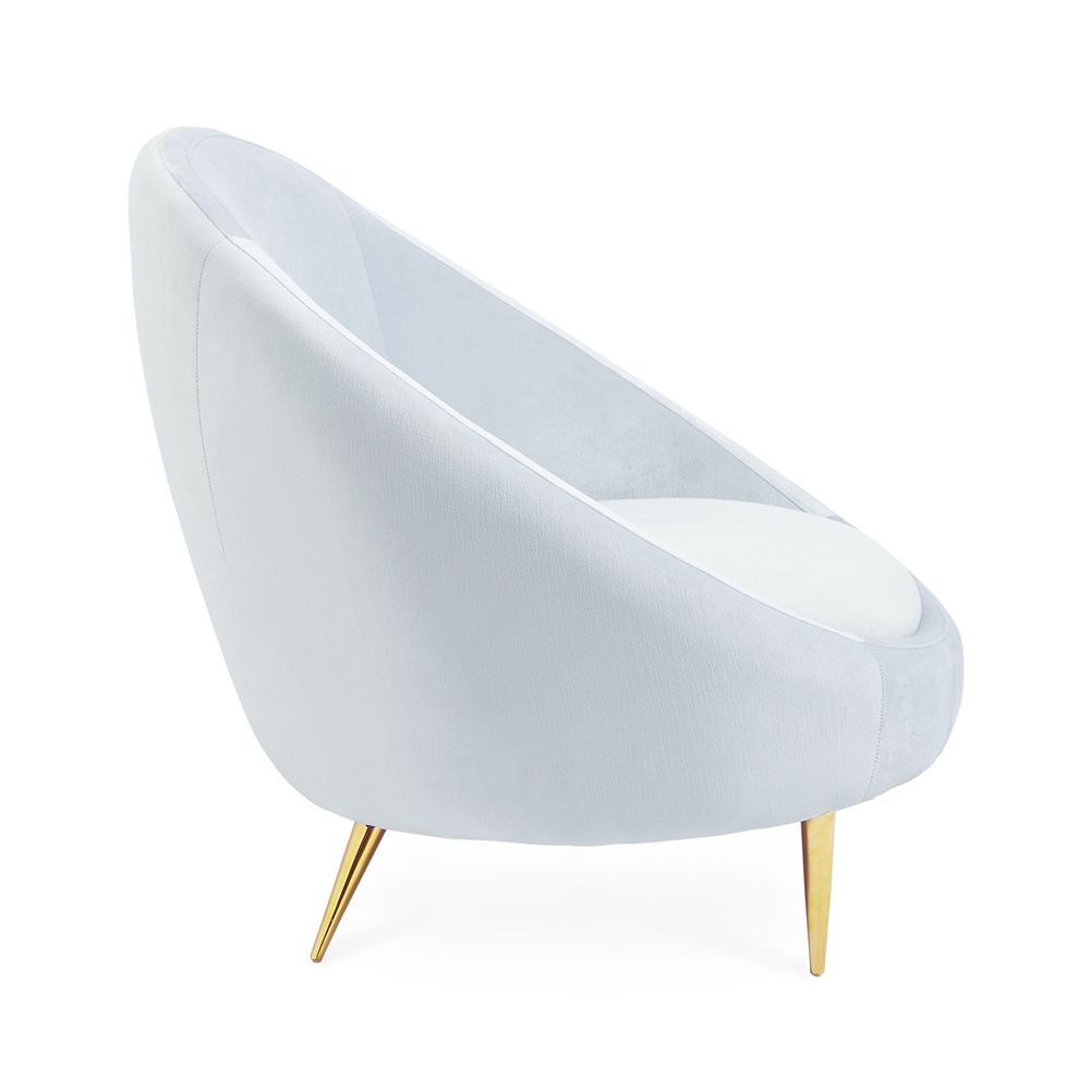 A stylish, modern armchair with light blue velvet upholstery and polished brass legs 