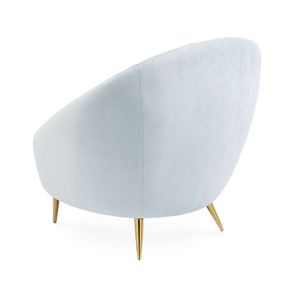 A stylish, modern armchair with light blue velvet upholstery and polished brass legs 