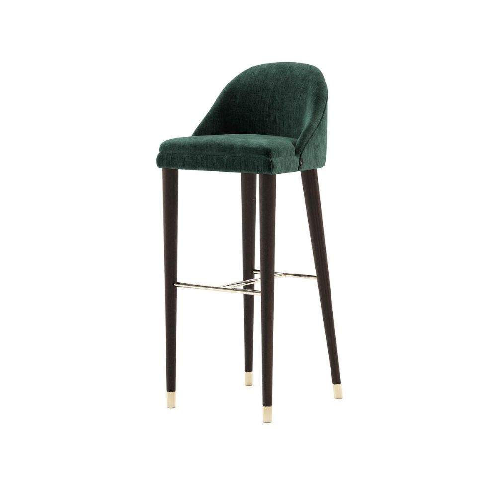 A luxurious bar stool with velvet upholstery and wooden legs with metallic details. Pictured in Vienna Green.