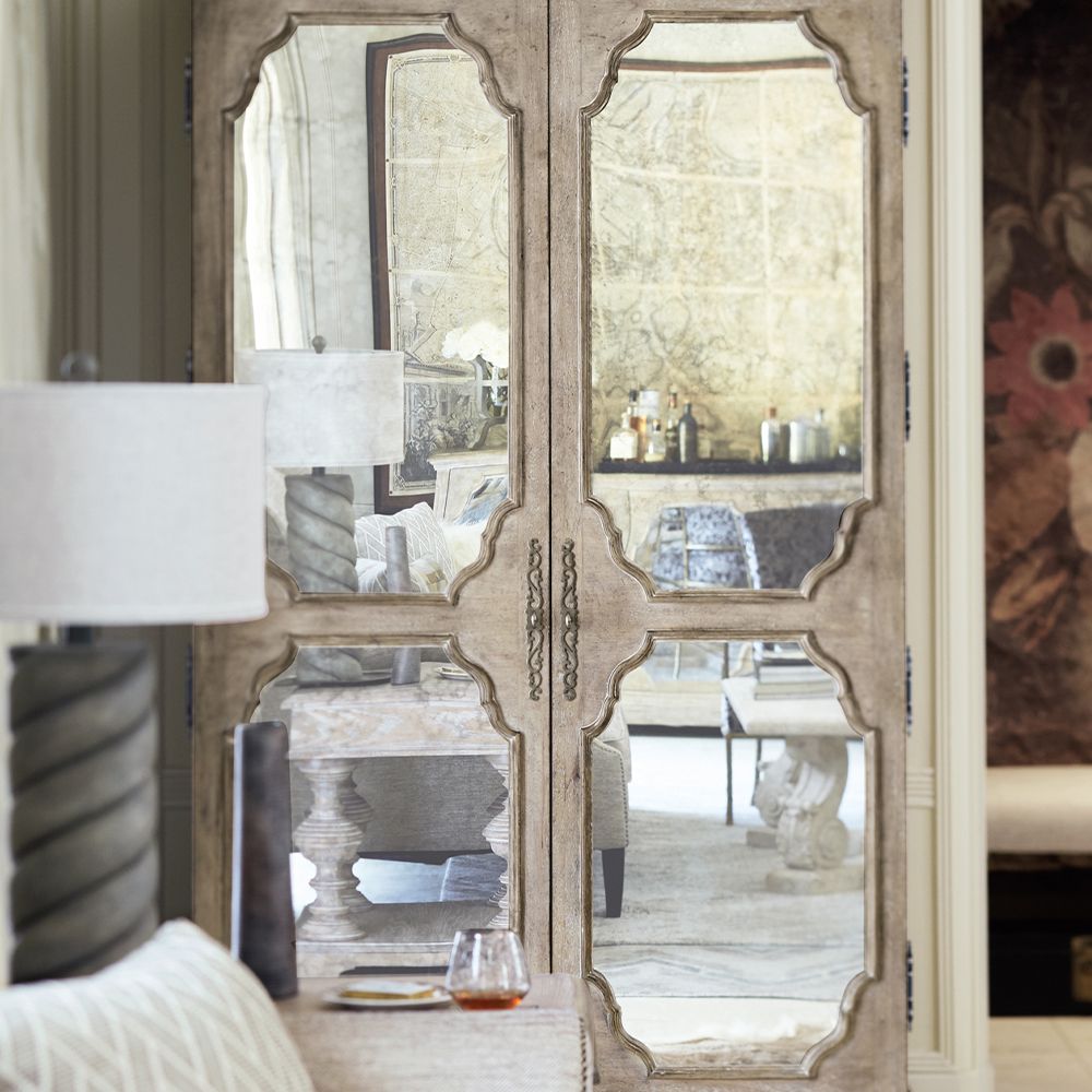 A beautiful armoire by Bernhardt featuring two wood-framed doors with antique mirrored glass panels