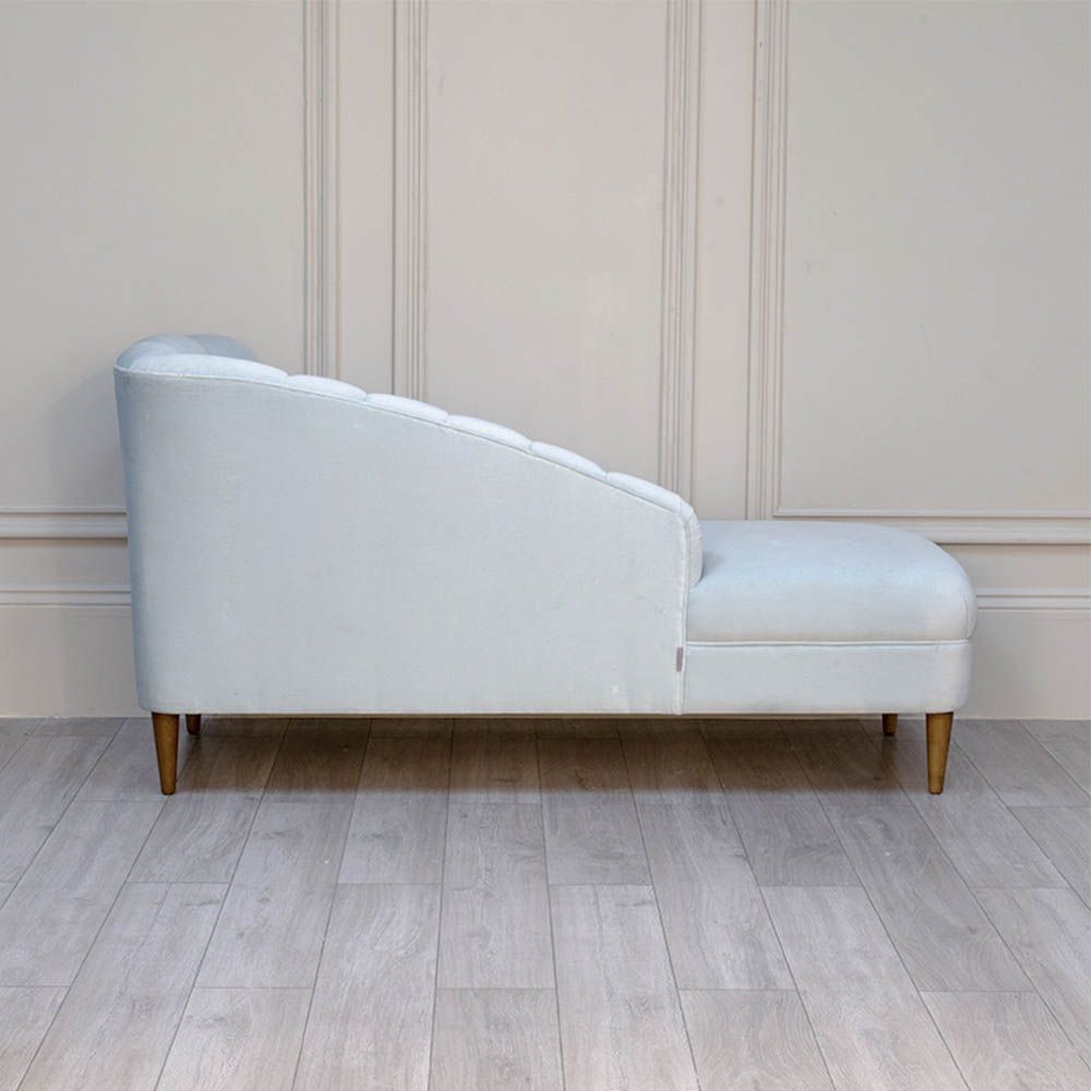 A curvaceous chaise longue with a pale blue velvet upholstery and seashell-like frame 