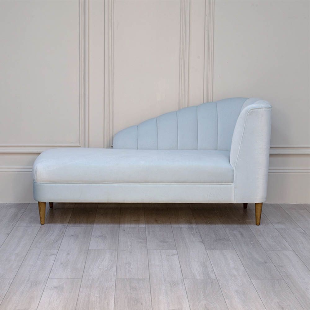 A curvaceous chaise longue with a pale blue velvet upholstery and seashell-like frame 