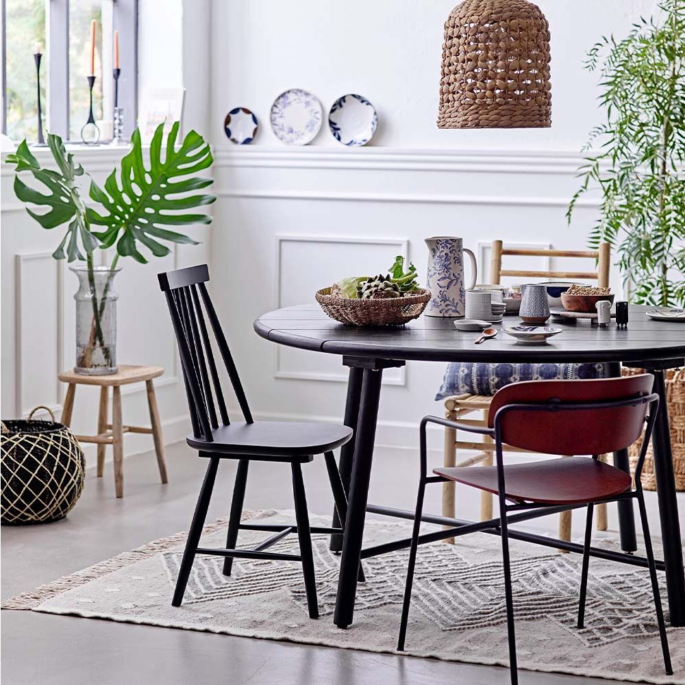 A sophisticated, rounded dining table made from black stained acacia wood