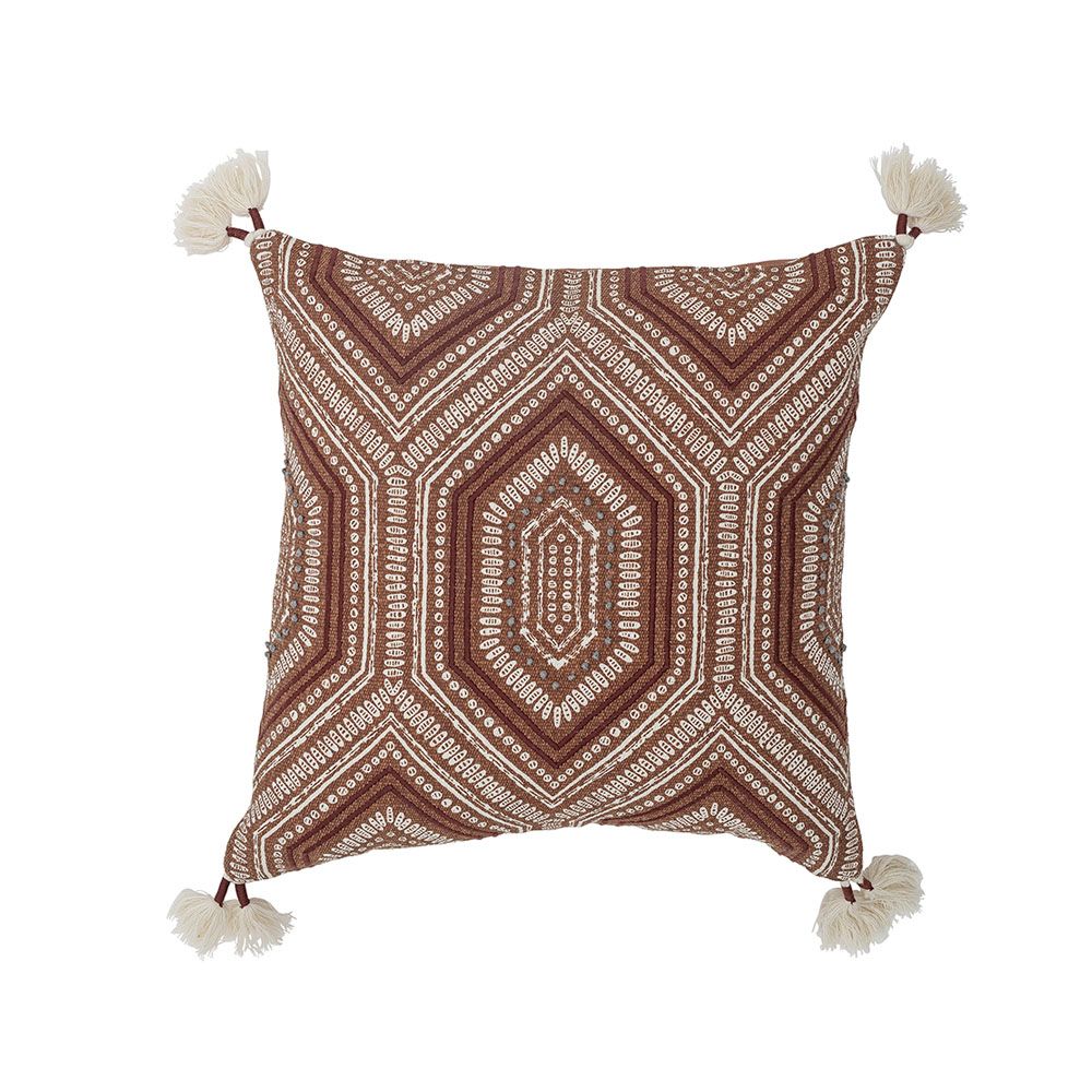 A warm cushion with an intricate embroidered pattern on warm brown linen with added tufted tassel details on each corner
