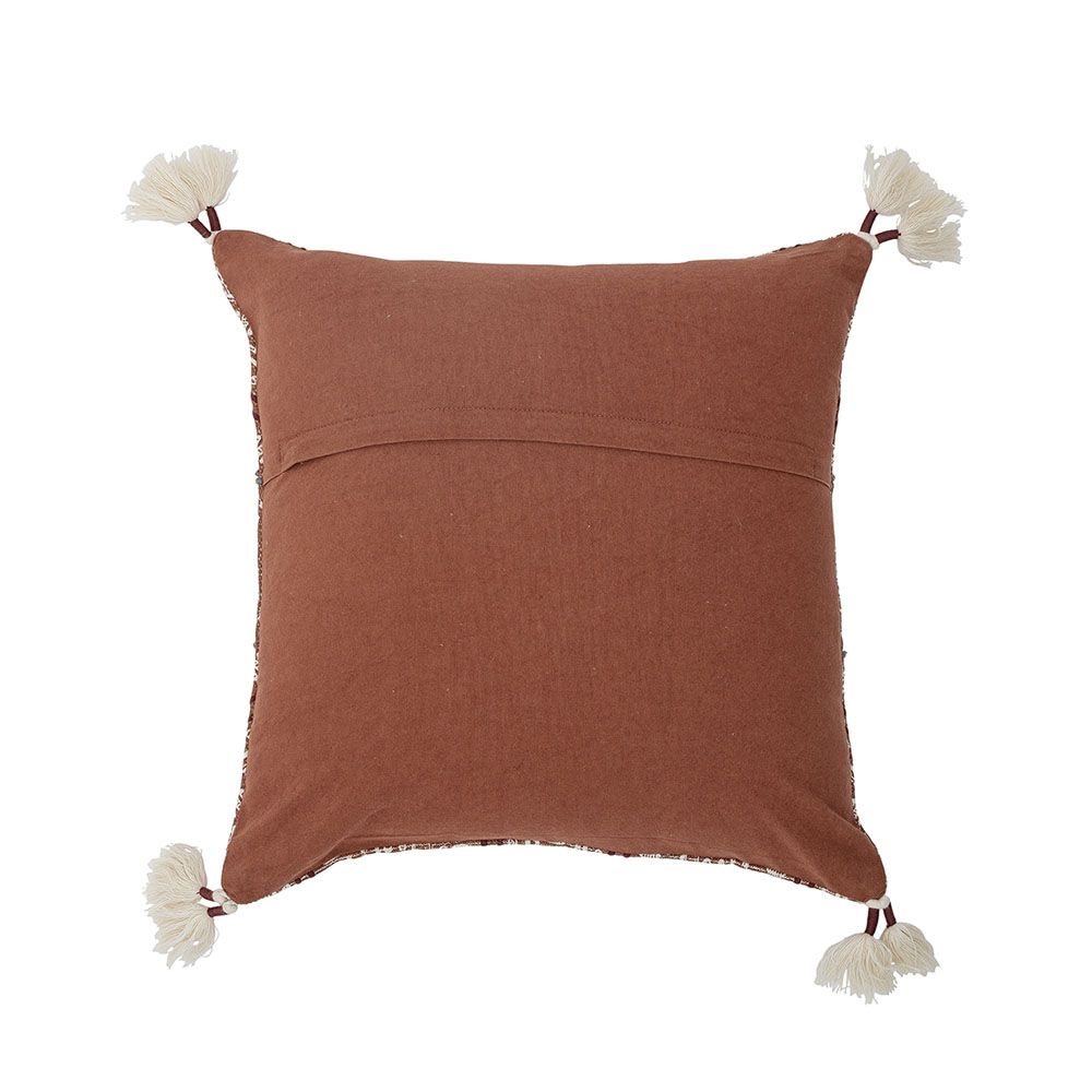 A warm cushion with an intricate embroidered pattern on warm brown linen with added tufted tassel details on each corner