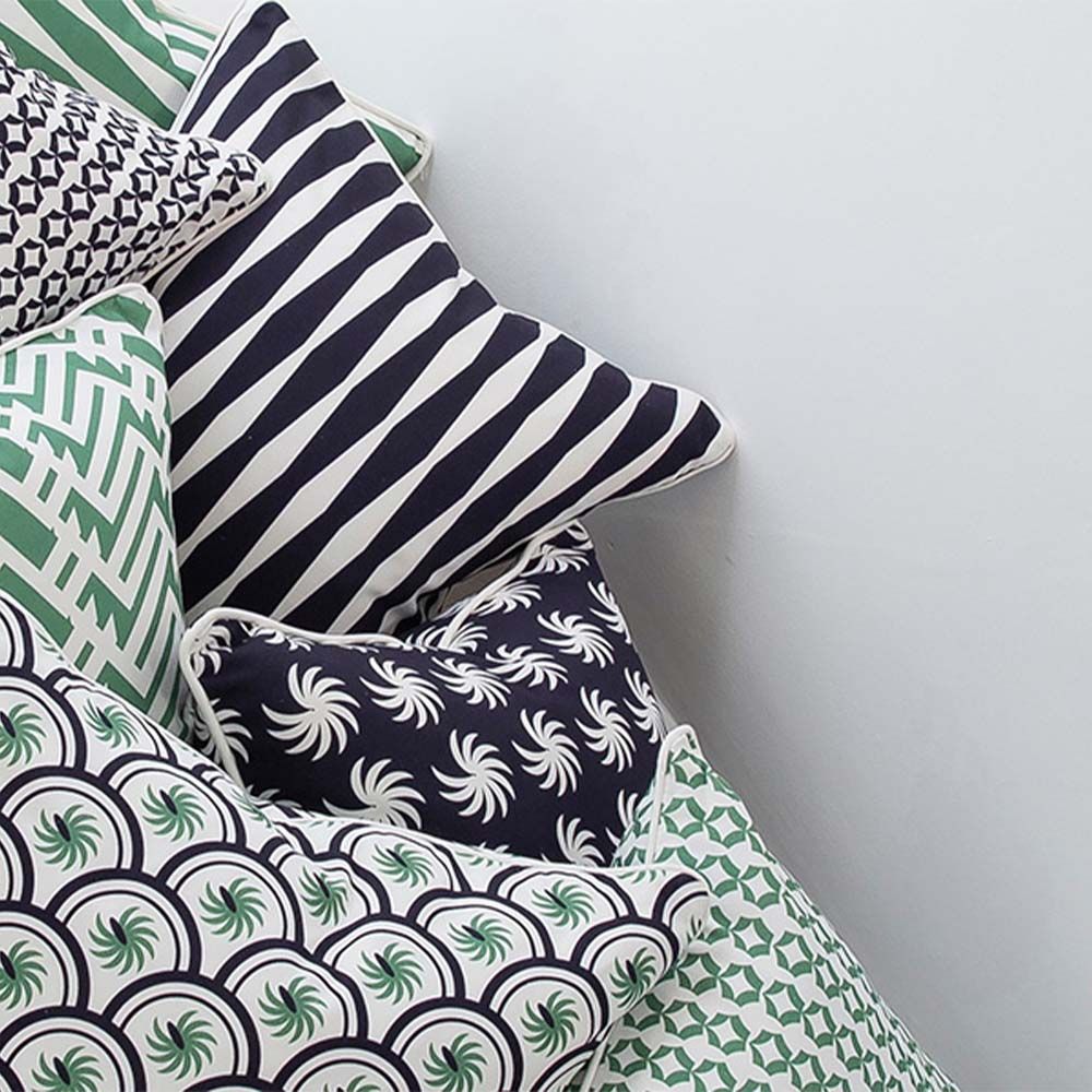 A dark blue square cushion with a white, palm-like design