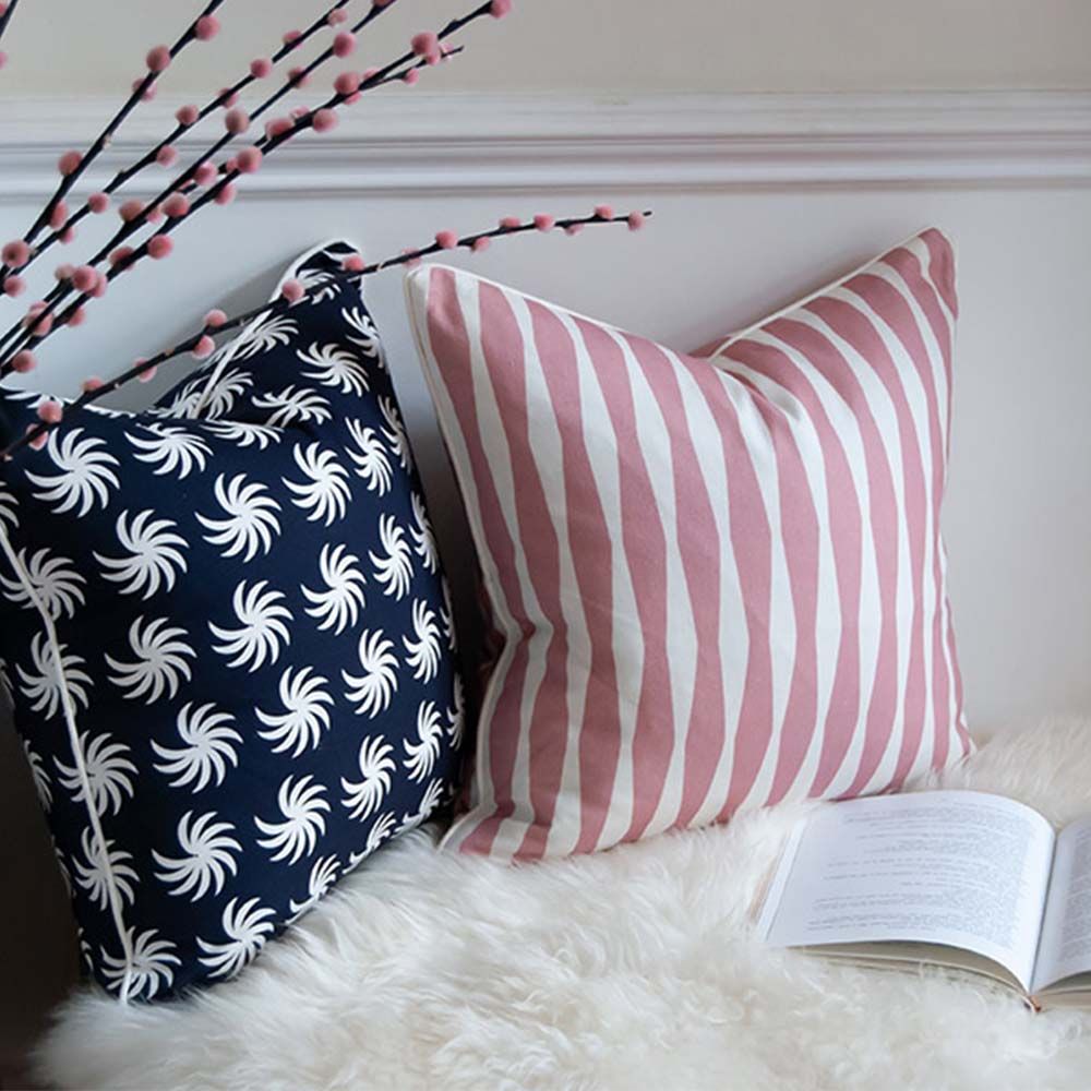 A dark blue square cushion with a white, palm-like design