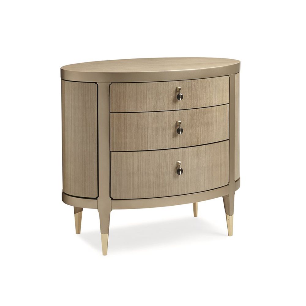A glamourous bedside table with a curved design and champagne finish