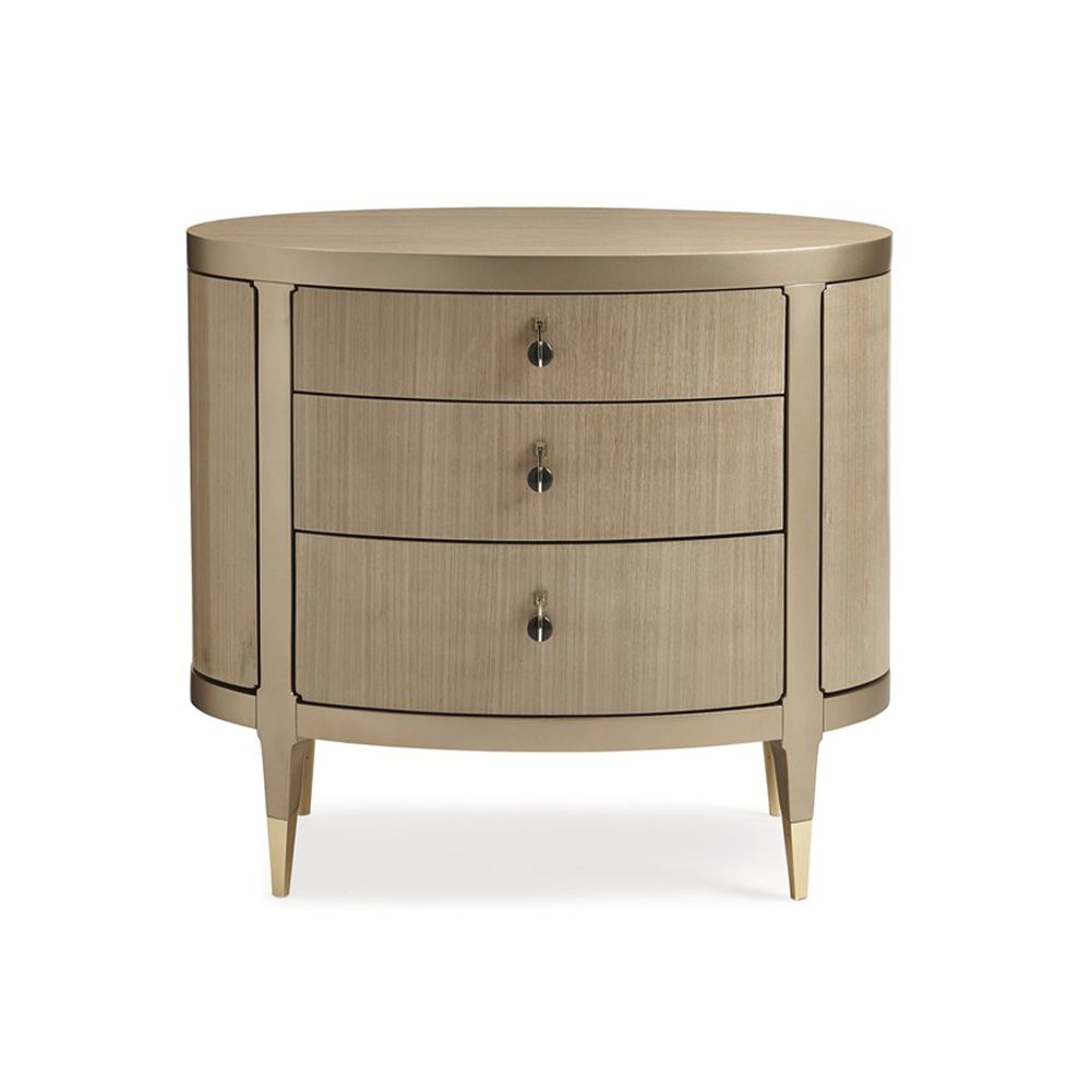 A glamourous bedside table with a curved design and champagne finish