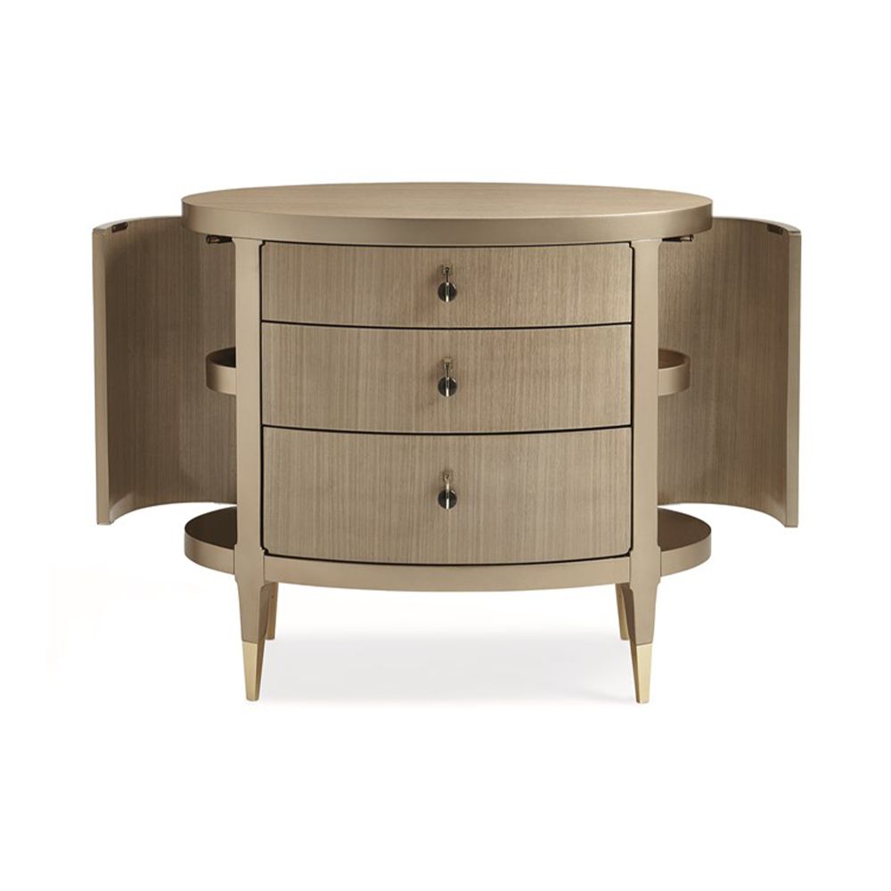 A glamourous bedside table with a curved design and champagne finish
