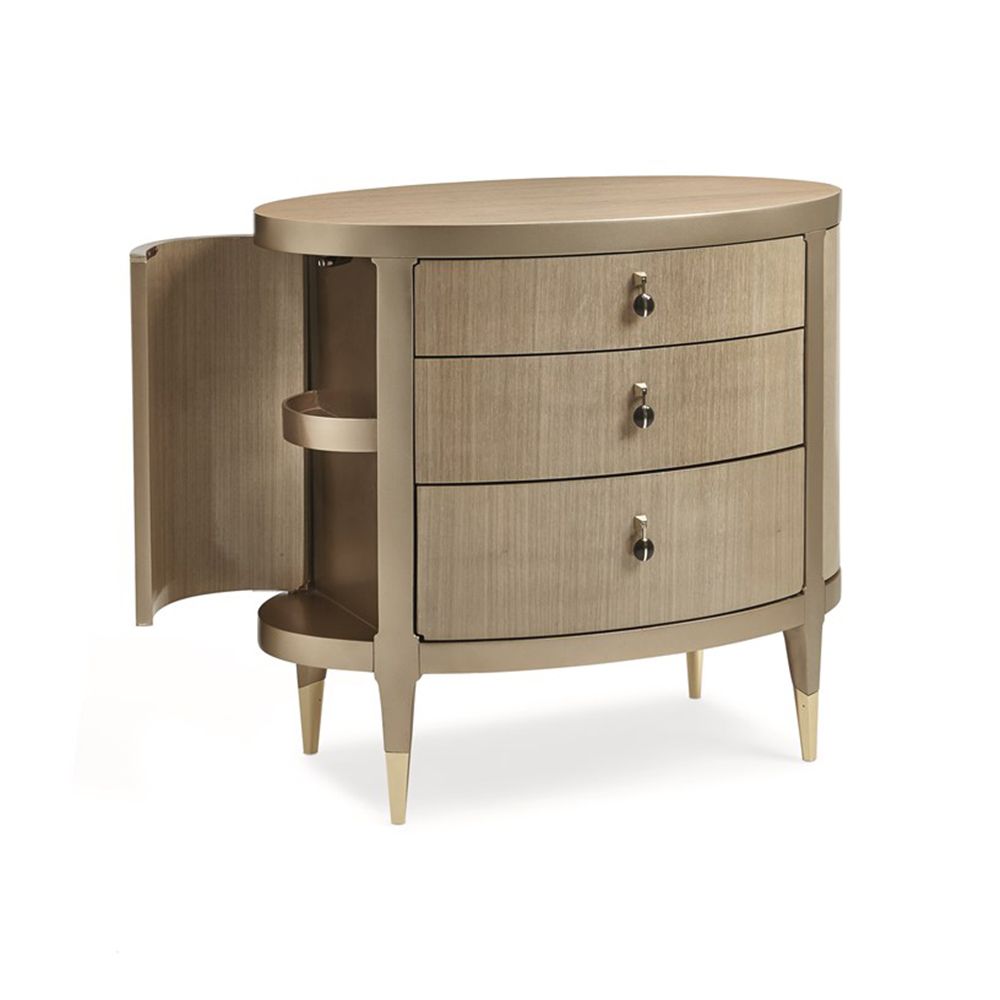A glamourous bedside table with a curved design and champagne finish
