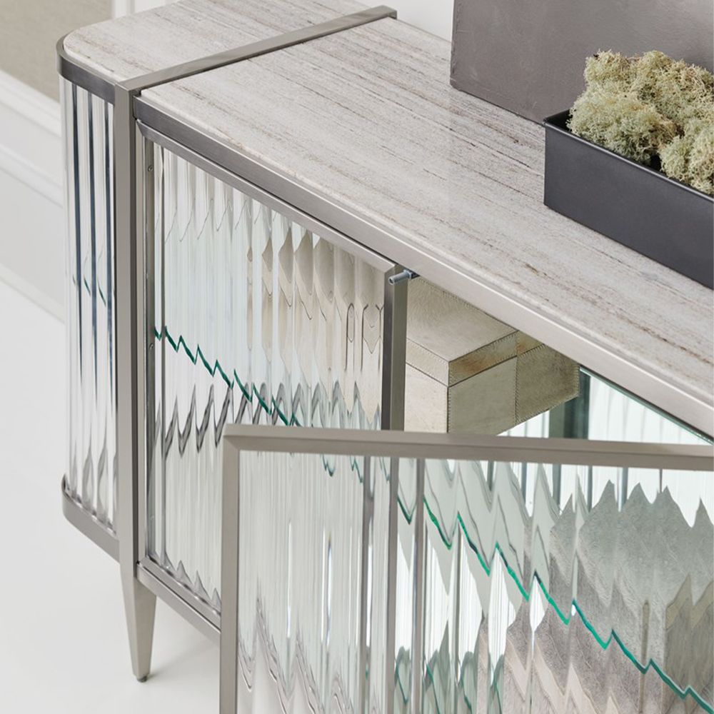 A contemporary console table by Caracole with clear, wave-effect acrylic doors and a mirrored interior