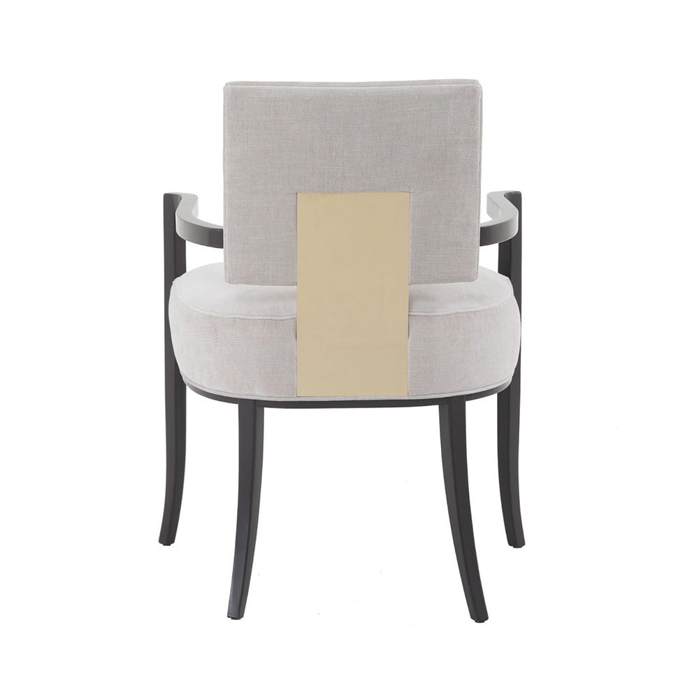 A contemporary dining chair by Caracole with a curved frame, grey upholstery and gold panel