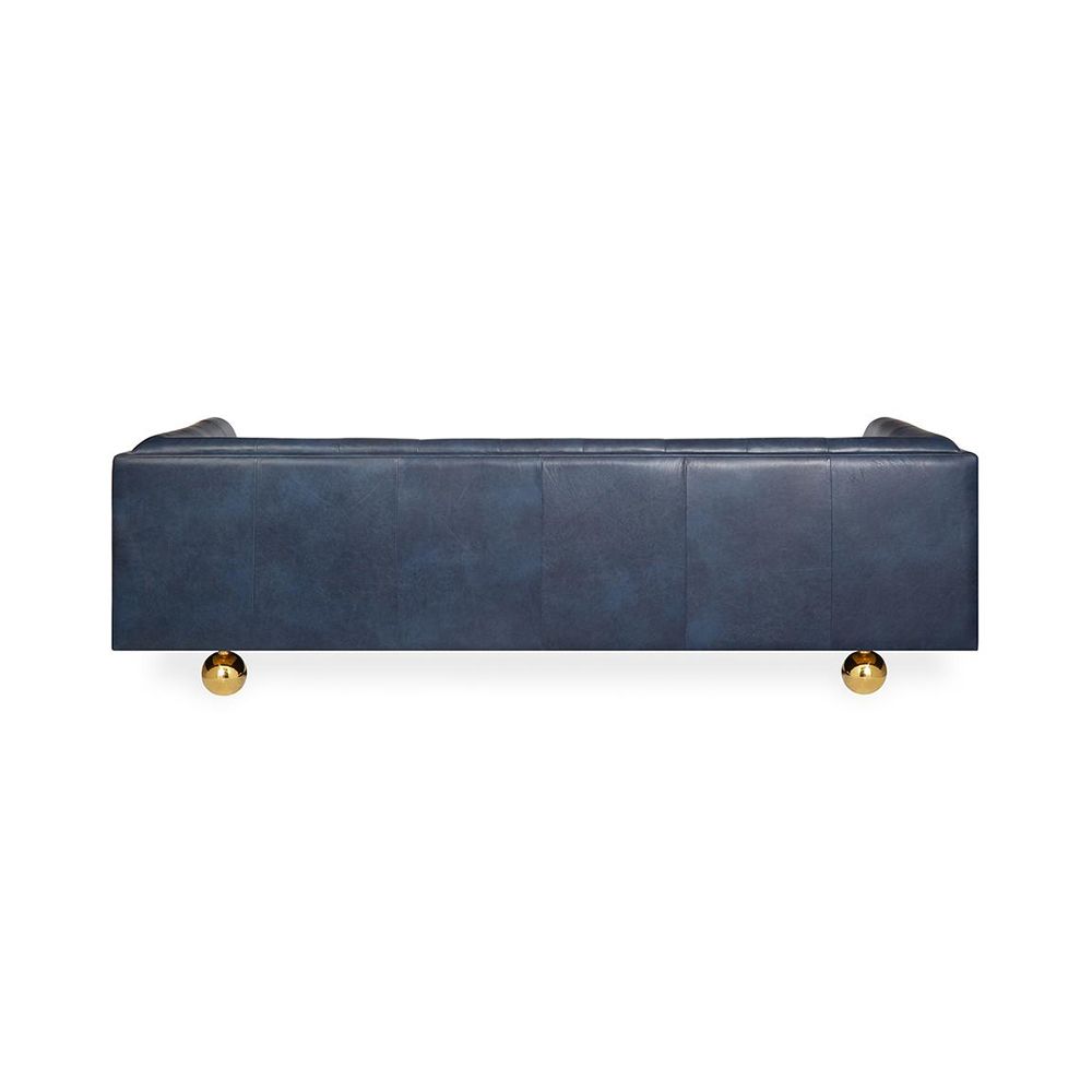 A luxurious modern sofa with navy leather upholstery and brass feet 