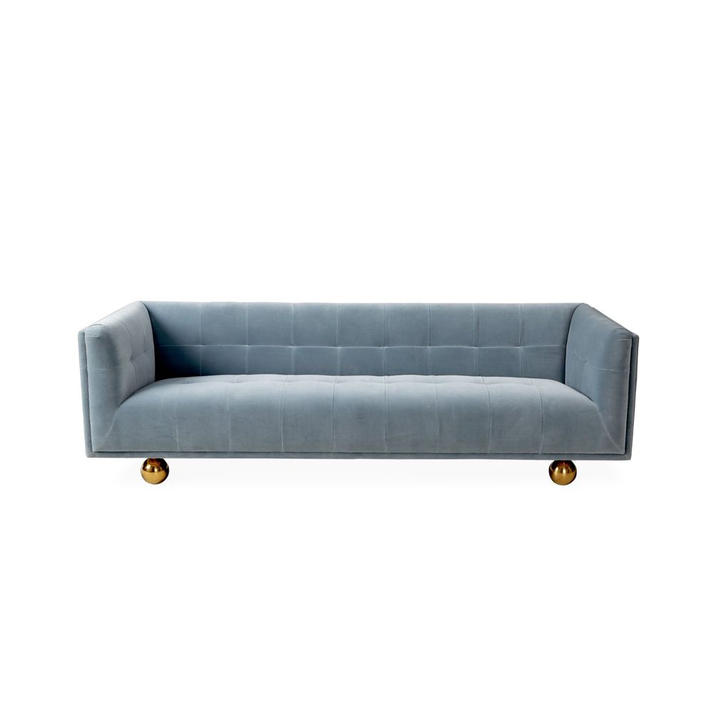 A luxurious pastel blue velvet sofa with golden orb feet
