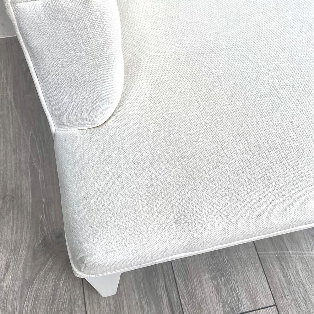A luxurious linen-upholstered bench with white legs