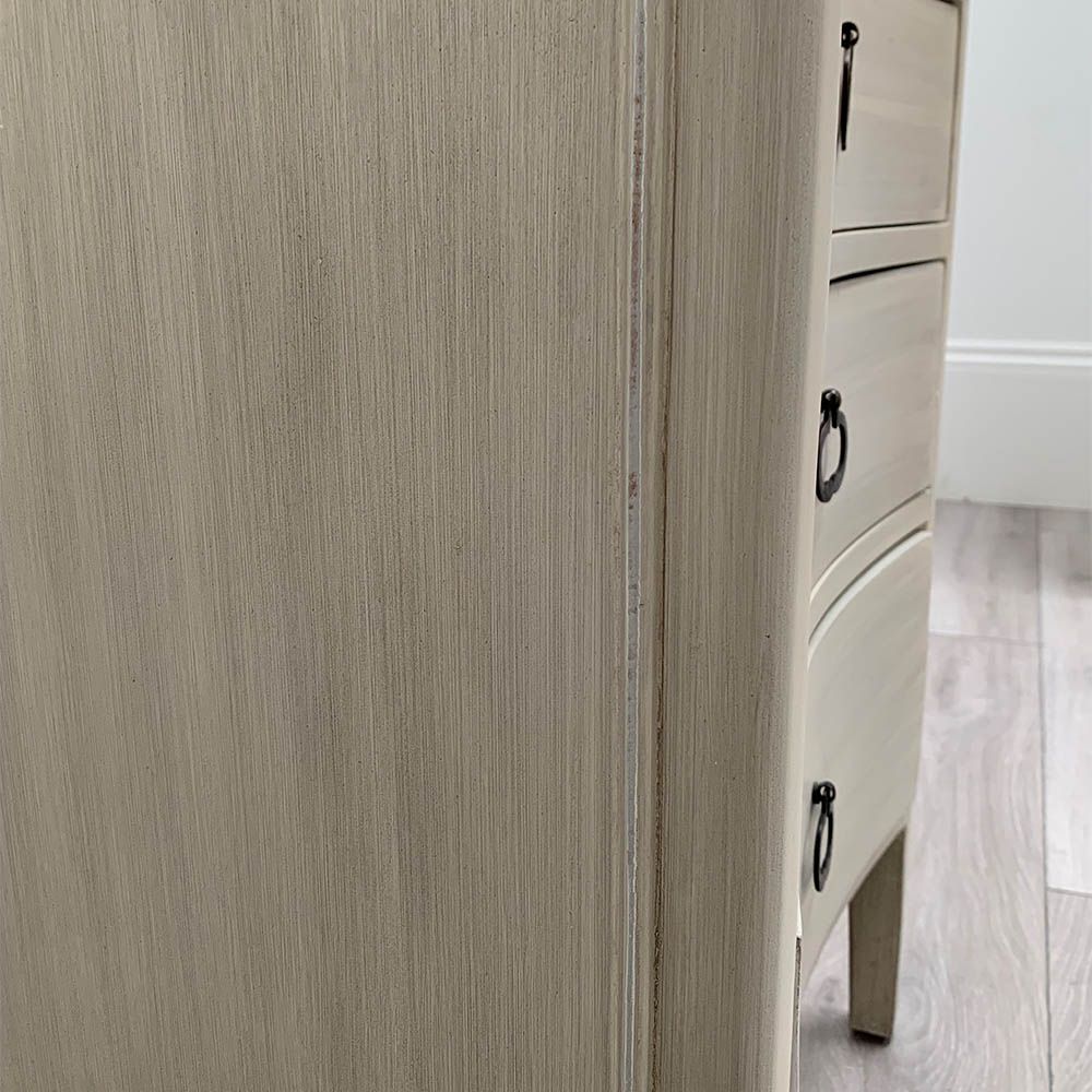 White washed three door bedside cabinet with some splits to the wood. 