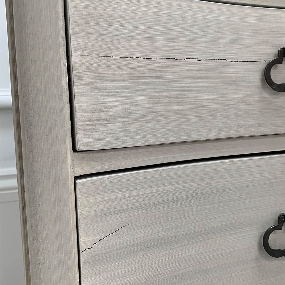 White washed three door bedside cabinet with some splits to the wood. 