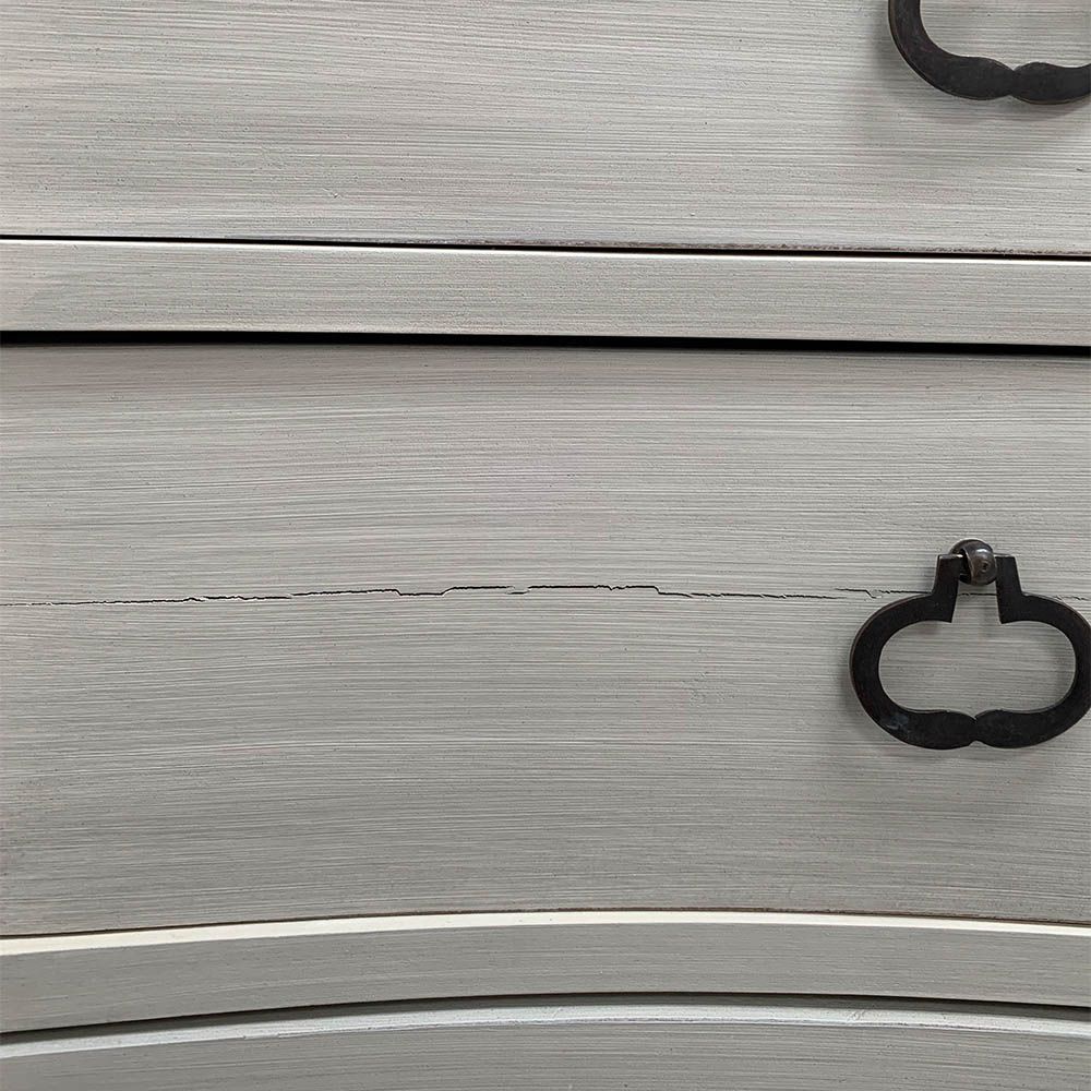 White washed three door bedside cabinet with some splits to the wood. 