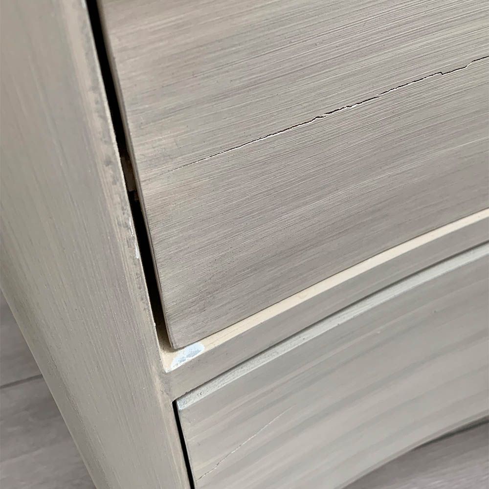 White washed three door bedside cabinet with some splits to the wood. 