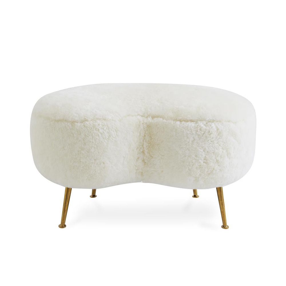 A chic, kidney-shaped shearling ottoman with polished brass legs 