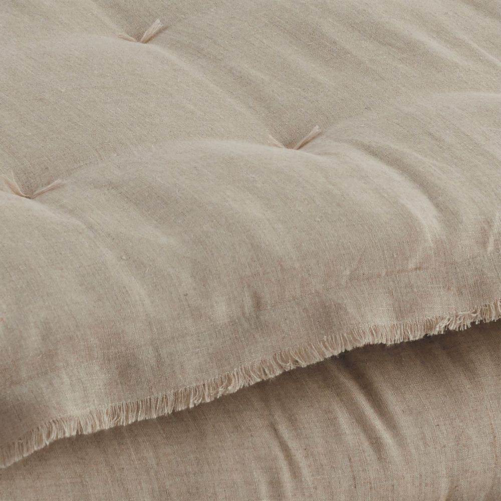 A gorgeous natural-toned quilt  with fringed details