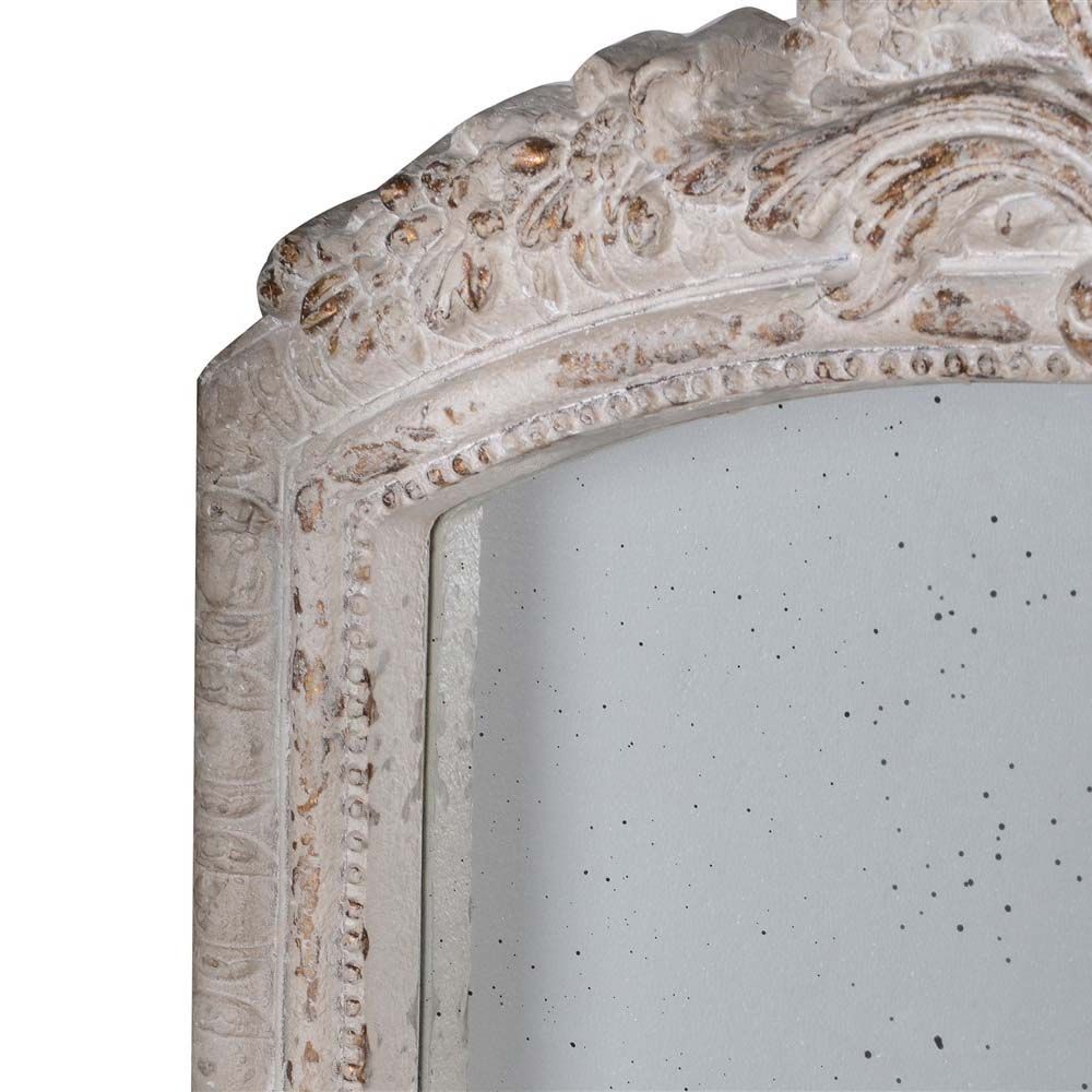 A distressed mirror adorned with an arch top and speckled glass