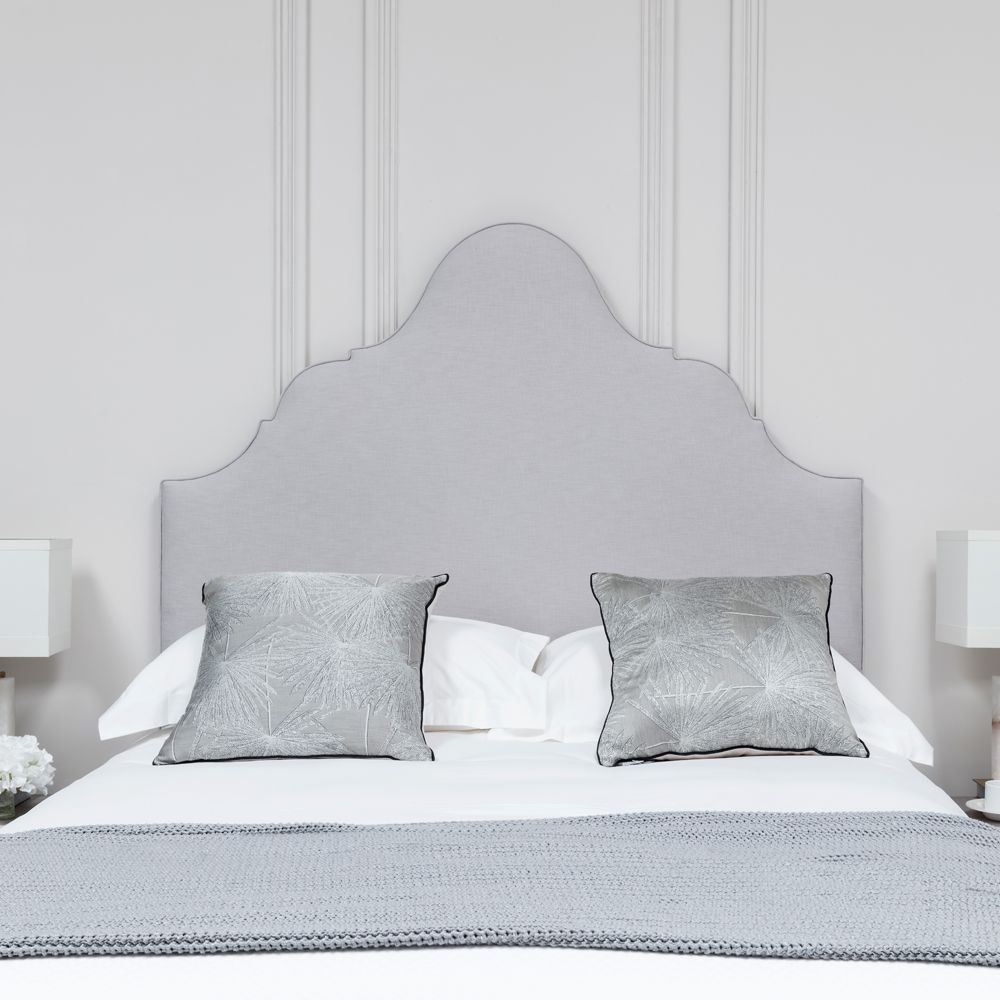 An elegantly upholstered bed with shaped headboard