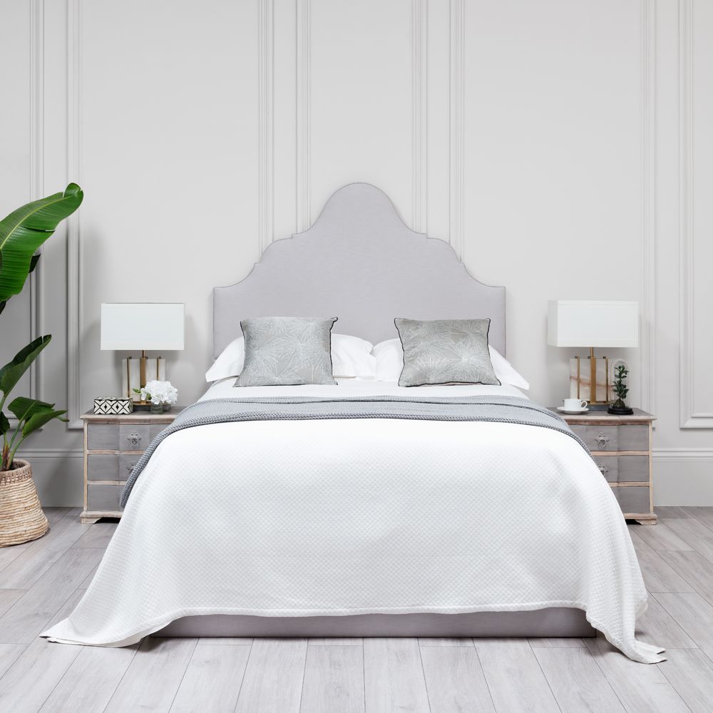 An elegantly upholstered bed with shaped headboard