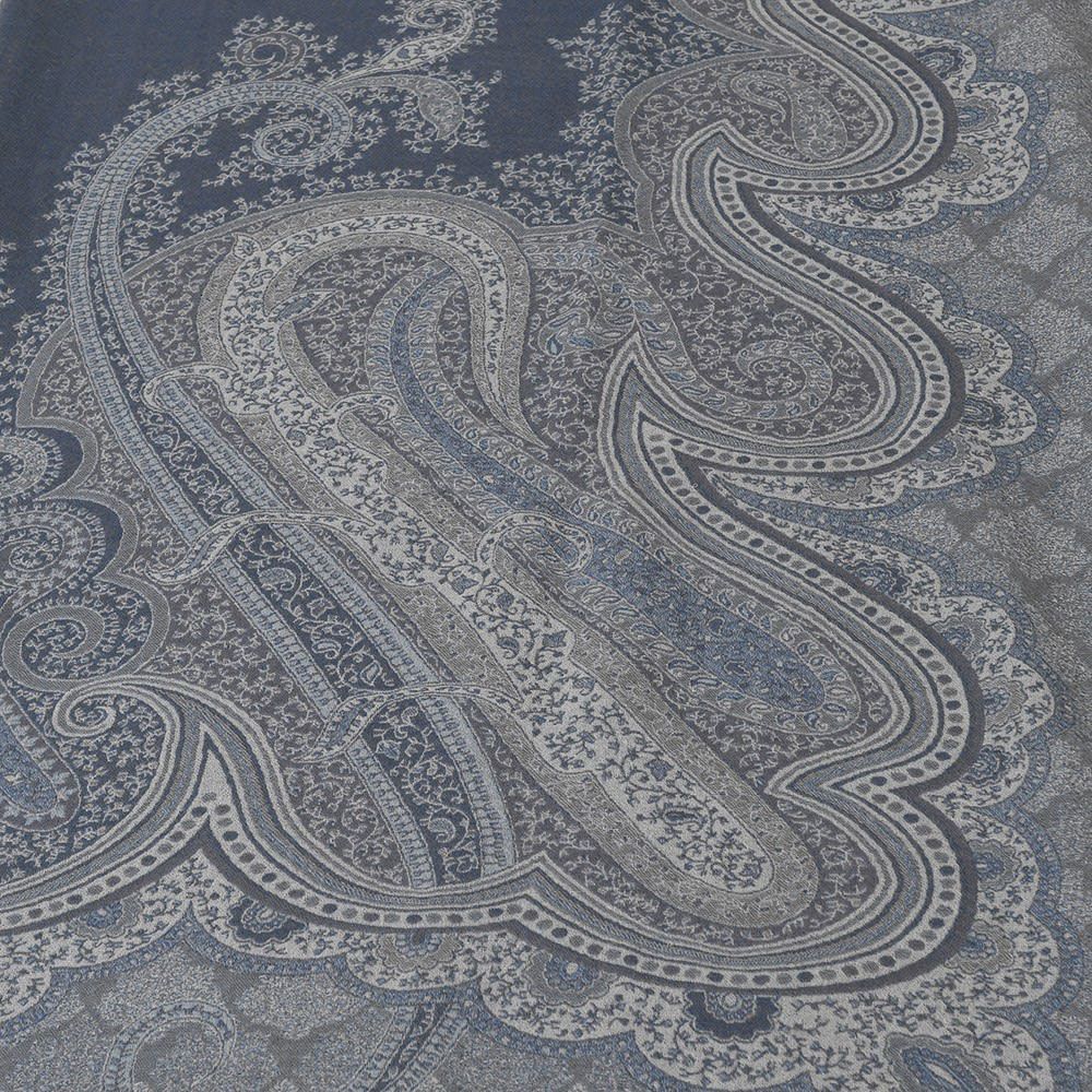 A luxurious blue and grey throw with elaborate, woven detailing and tassels